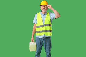 Mature male worker with canister on green background