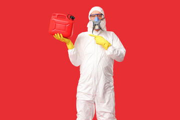 Mature man in protective uniform pointing at canister on red background