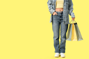 Naklejka premium Young woman with shopping bags on yellow background, closeup