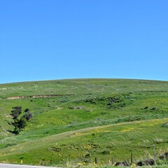 Rolling green hills under bright blue sky showing peaceful countryside terrain