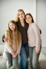 portrait of beautiful blonde smiling mother and daughter with long hair posing in white studio
