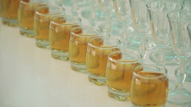 Glasses with alcohol in a row on a white table
