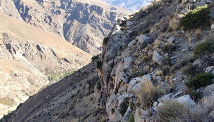 Steep rocky cliff overlooking deep valley showing rugged natural terrain