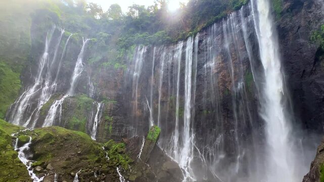 The multi-tiered Tumpak Sewu waterfall, with its lush greenery and wide stream of water flowing into a deep, semi-circular basin on the island of Java. Near Mount Semeru. Indonesia. 4К