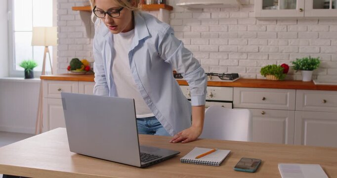 Tired female freelancer, worker feels backache after sitting at desk, working online laptop, touching back suffering from lower spinal spasm, hurt unhealthy woman incorrect posture, working from home 