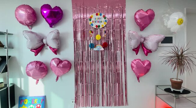Colorful home birthday party decoration with balloons, ribbons, and happy birthday banner in cozy living room interior
