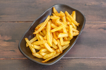 Frites, side dish dans un bol noir sur une table en bois