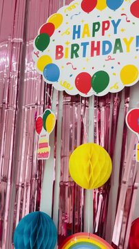 Colorful home birthday party decoration with balloons, ribbons, and happy birthday banner in cozy living room interior
