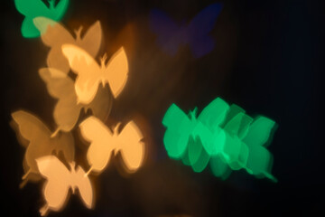 Yellow and green butterfly bokeh photo on black background – abstract flying butterflies, front view