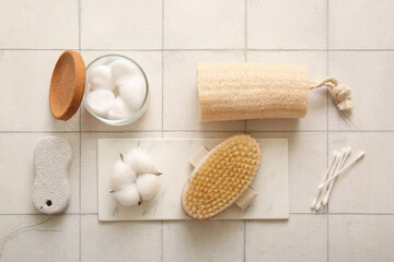 Massage brush with cotton swabs, loofah and pumice on white tile background