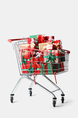 Shopping cart with Christmas gift boxes and candy canes on white background © Pixel-Shot