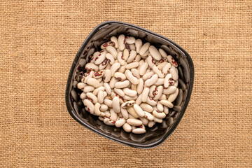 White uncooked beans on jute cloth, macro, top view.