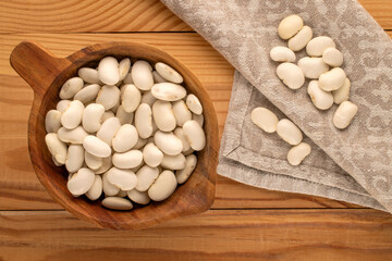 White uncooked beans on a wooden table, close-up, top view.