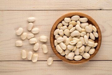 White uncooked beans on a wooden table, close-up, top view.
