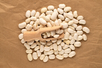 White uncooked beans on kraft paper, close-up, top view.