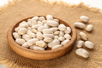 White uncooked beans on jute cloth, macro.