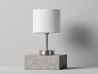 Minimalist table lamp with white shade, brushed metal base, on a textured concrete block