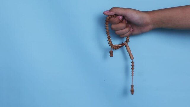 A hand holding a wooden set of prayer beads. This is usually used for zikr in Islam