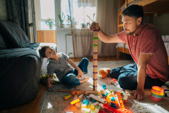 Father and son playing with building blocks at home during the day