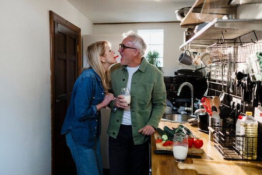 Senior couple playfully interacting in the kitchen with food and drinks