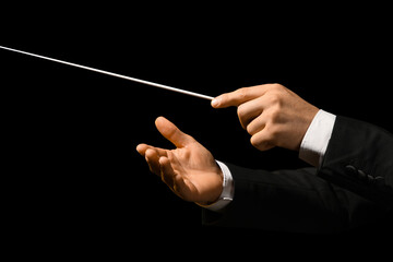 Hands of male conductor with baton on black background