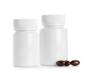 Blank plastic vitamin bottles and brown pills on white background