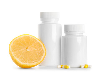 Blank plastic vitamin bottles with pills and lemon on white background