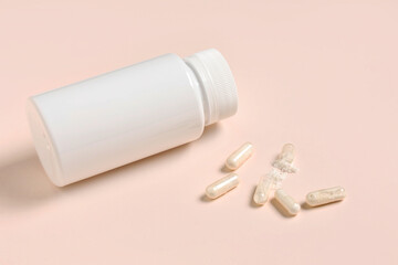 Blank plastic vitamin bottle and pills on beige background
