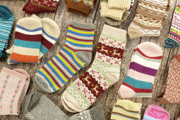 Lots of warm colorful socks on a wooden background. Socks for fall and winter. Warm knitted clothes.