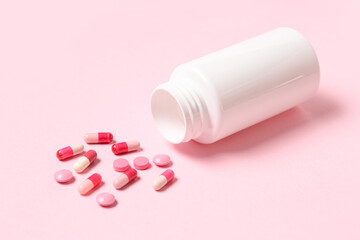 Blank plastic vitamin bottle and different pills on pink background