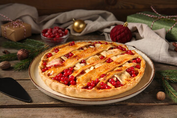 Plate with tasty cranberry pie, Christmas balls and fir branches on wooden background