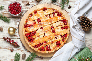 Tasty cranberry pie with cinnamon and Christmas tree branches on white wooden background