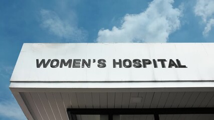 Women’s Hospital word sign displayed on a large medical building under a clear blue sky, symbolizing specialized healthcare, maternity services, female wellness, medical care, and dedicated health