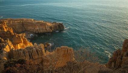 Coastal Cliffscape at Dawn Layered Rocks, Turquoise Sea, and Bare Branches.