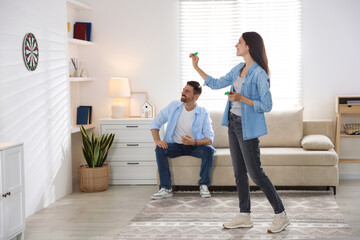 Man and woman playing darts at home