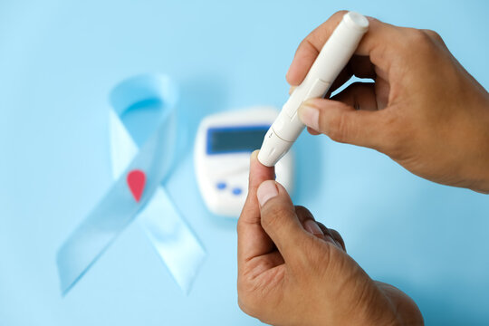 World diabetes day and blue ribbon awareness with red blood drop in woman hands isolated on a blue background. World diabetes day,14 november. Copy space. Top view - Powered by Adobe