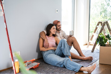 Happy young couple sitting with coffee cup at home