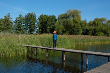 A boy fishing on a bridge on a lake