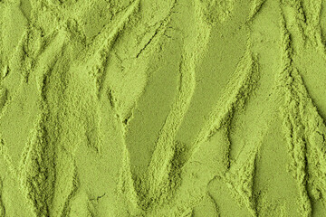 Flowing textured surface of green matcha powder creates a dynamic, natural background perfect for...