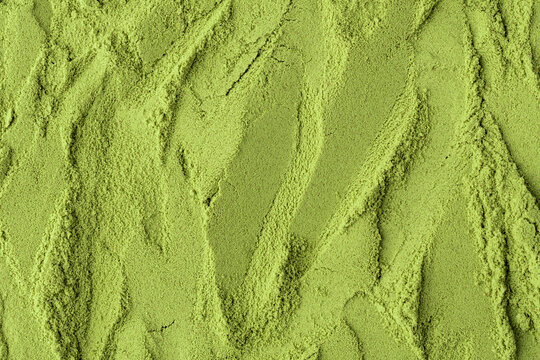 Flowing textured surface of green matcha powder creates a dynamic, natural background perfect for health, food, or branding visuals.