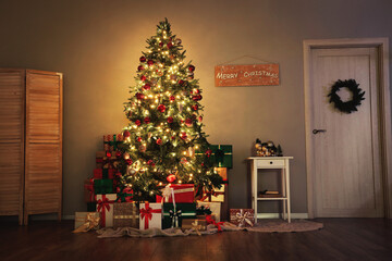 Decorated Christmas tree with glowing lights, many gifts and coffee table in living room at night