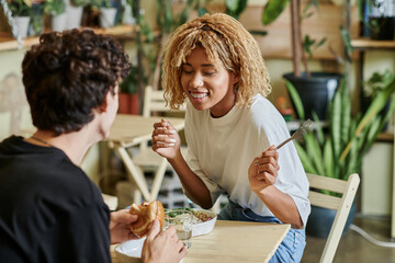 Stylish couple sharing a delightful meal in a cozy cafe filled with greenery