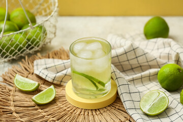 Decorative podium with glass of lime infused water on white table against yellow background