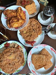 Top view of traditional Indonesian meal with crispy omelette, fried tempeh, and banana fritters served with chili and rice. Authentic local cuisine representing comfort food and culinary heritage.