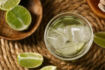 Glass of lime infused water on wicker mat, closeup