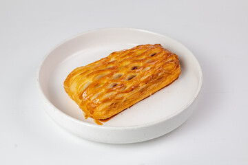 Golden lattice-top pastry on minimalist white plate against clean studio background