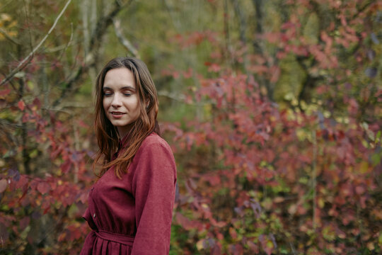 A candid portrait of a young woman among autumn foliage, capturing authenticity and quiet confidence with natural light, soft expression and an unposed, true-to-life mood and tone.