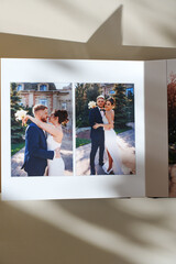 page of an open photo book with wedding photos on a white table