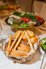 Rustic bread basket with assorted loaves and baguettes beside vegetable platter