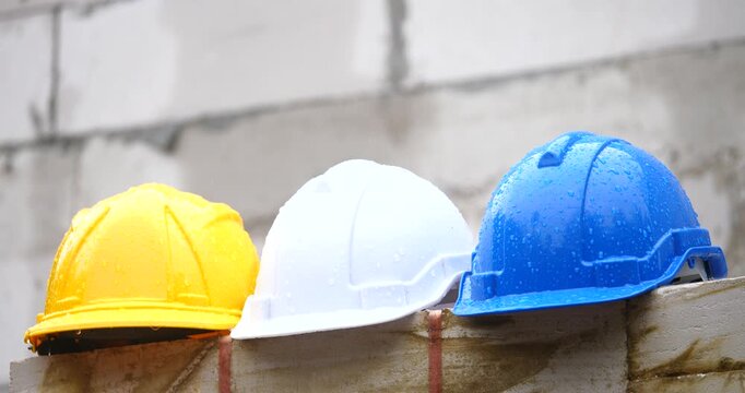 Safety Helmets on Construction Site: A row of vibrant safety helmets, each in a distinct color, rests against a textured brick backdrop, symbolizing the core principles of construction.